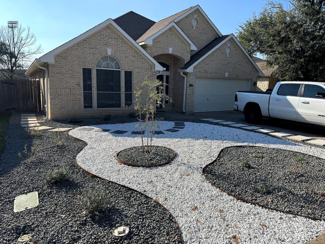 Modern home exterior with gravel landscaping, white rocks, and a small tree in the garden.