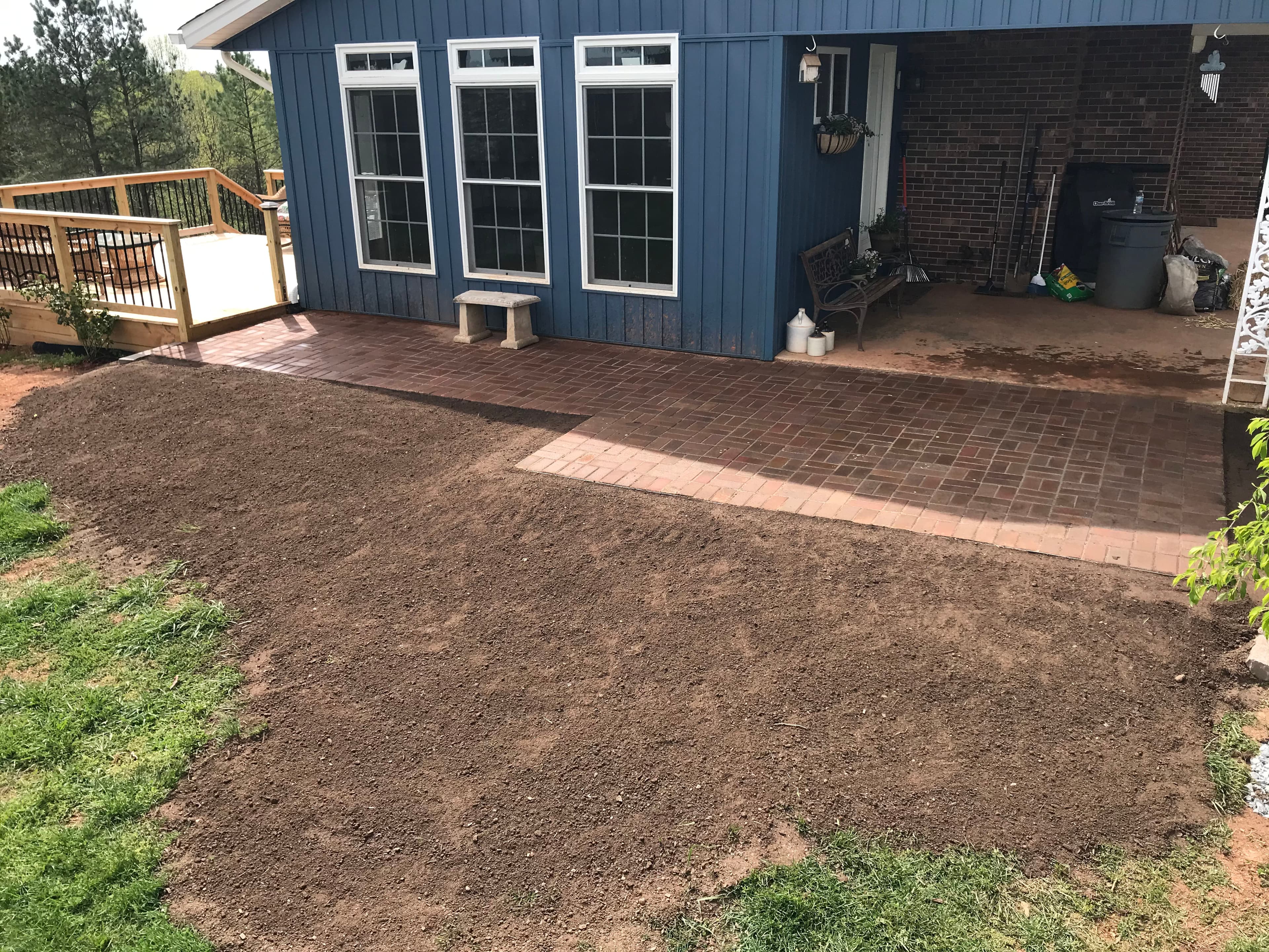 Patio area with newly laid brick pavers next to an unprepared garden plot.