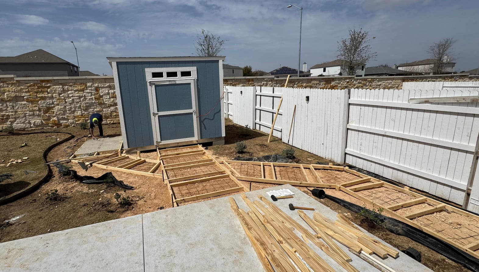 Construction of a garden shed with wooden pathways in a backyard landscape.