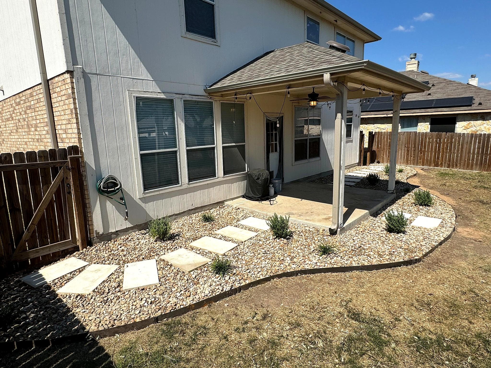 Backyard landscape design featuring a stone path, gravel, and low-maintenance plants.