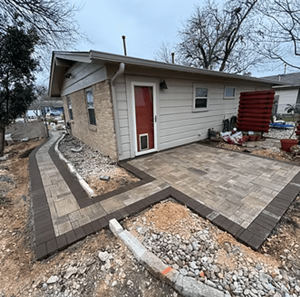 Renovated home exterior with new paver patio and landscaped pathway. Modern design features.